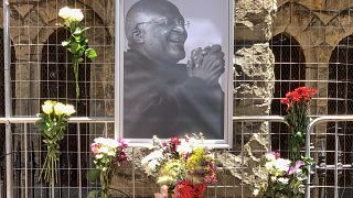 أزهار بجوار صورة لأيقونة جنوب إفريقيا المناهضة للفصل العنصري ديزموند توتو خارج كاتدرائية سانت جورج، في كيب تاون، في 26 ديسمبر 2021