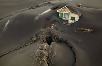 A fissure is seen next to a house covered with ash on the Canary island of La Palma