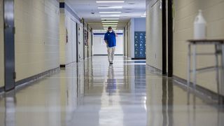 A middle school principal walks the empty halls of his school as he speaks with one of his teachers to get an update on her COVID-19 symptoms, Aug., 20, 2021, in Wrightsville.