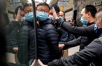 Le rédacteur en chef de Stand News, Patrick Lam, escorté par des policiers après une perquisition dans son bureau à Hong Kong
