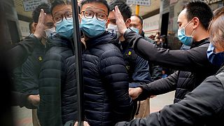Le rédacteur en chef de Stand News, Patrick Lam, escorté par des policiers après une perquisition dans son bureau à Hong Kong