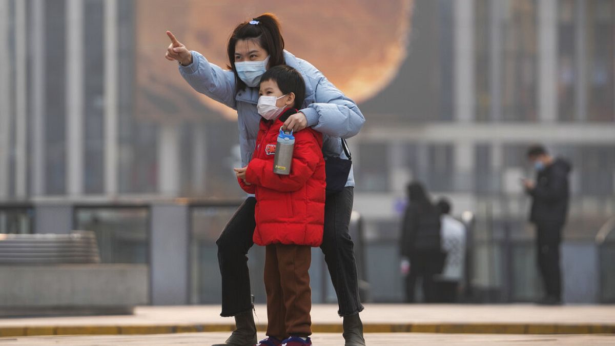 Une femme et un enfant, portant des masques, à Pékin, le 28 novembre 2021