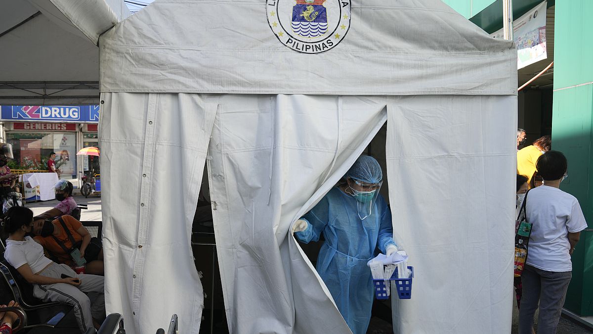Medical Technologist Erika Alvarado comes out of a tent after she performs a COVID-19 test on a patient outside a hospital in Manila, Philippines on Friday, Dec. 24, 2021.