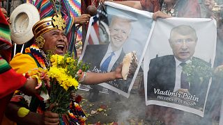 Shamans hold photos of Joe Biden & Vladimir Putin during a year-end ritual where they predict political & social issues expected to occur in 2022 in Lima, Peru, Dec. 29, 2021.