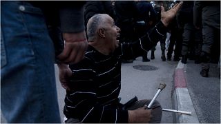 ناشط فلسطيني يصرخ على عناصر الشرطة الإسرائيلية بعد أن كسروا عكازيه خلال تظاهرة ضد إجلاء عائلات فلسطينية من منازلها في حي الشيخ جراح بالقدس الشرقية، 31 ديسمبر 2021