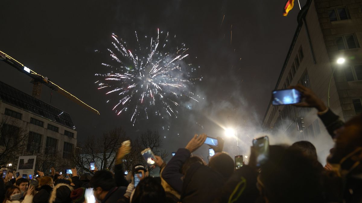 Spectators at the boulevard Unter den Linden watch fireworks as they celebrate the New Year near the Brandenburg Gate in Berlin, Germany, Jan. 1, 2022. 