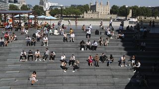 أناس يجلسون على مدارج تحت أشعة الشمس مع برج لندن في الخلفية في لندن. 2021/09/07