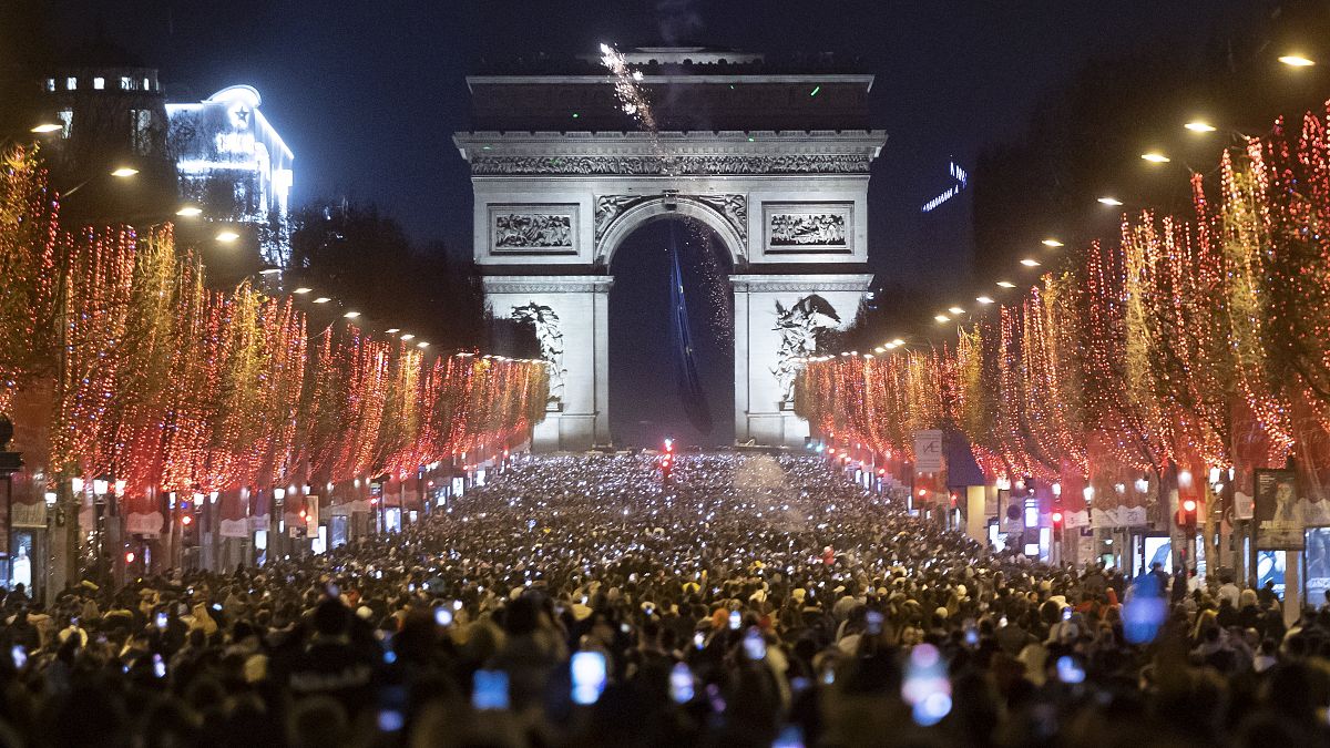 Az újév beköszöntét ünneplő emberek a párizsi Champs-Élyées sugárúton 2022. január 1-jén.
