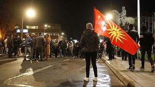 A woman with the old national flag stands in front of the parliament building in Skopje
