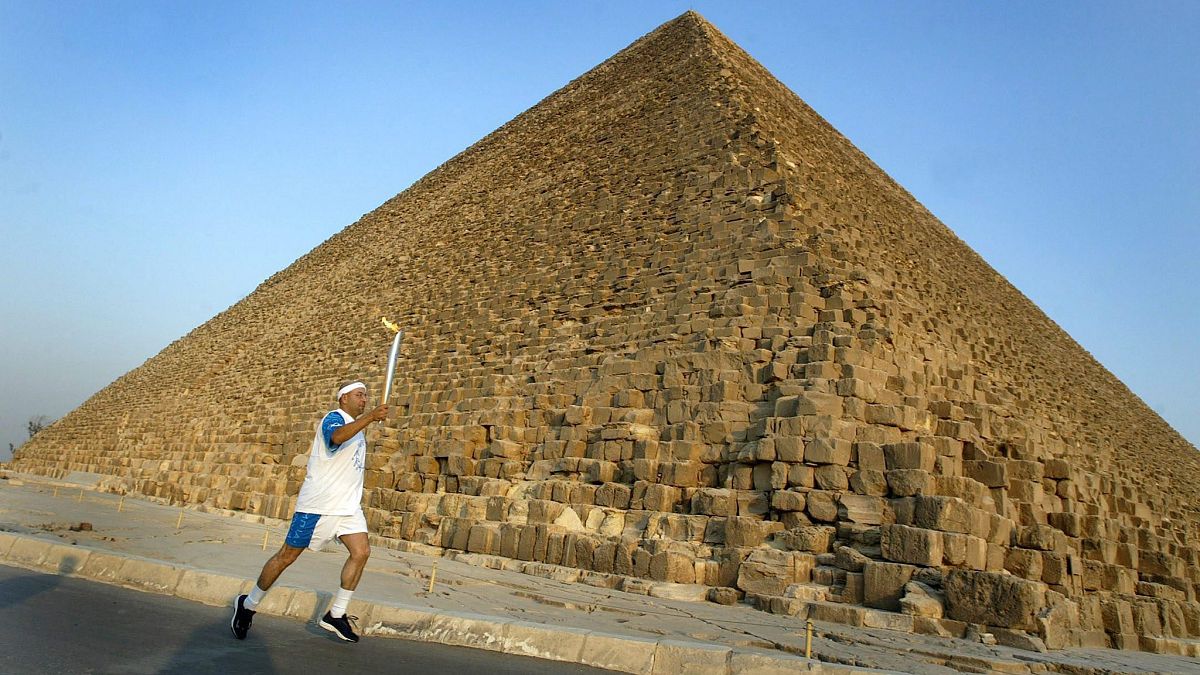 Az egyiptomi Ajman HUSZEIN viszi az olimpiai láng fáklyáját Kheopsz fáraó gízai piramisa előtt 2004. június 11-én.