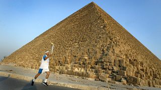 Az egyiptomi Ajman HUSZEIN viszi az olimpiai láng fáklyáját Kheopsz fáraó gízai piramisa előtt 2004. június 11-én.
