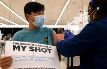 Lucas Kittikamron-Mora, 13, holds a sign in support of COVID-19 vaccinations as he receives his first Pfizer dose at the Cook County Public Health Department, May 13, 2021.