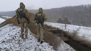 Ukrainian border guards watch as a special vehicle digs a trench on the Ukraine-Russia border close to Sumy, Ukraine, Dec. 21, 2021.