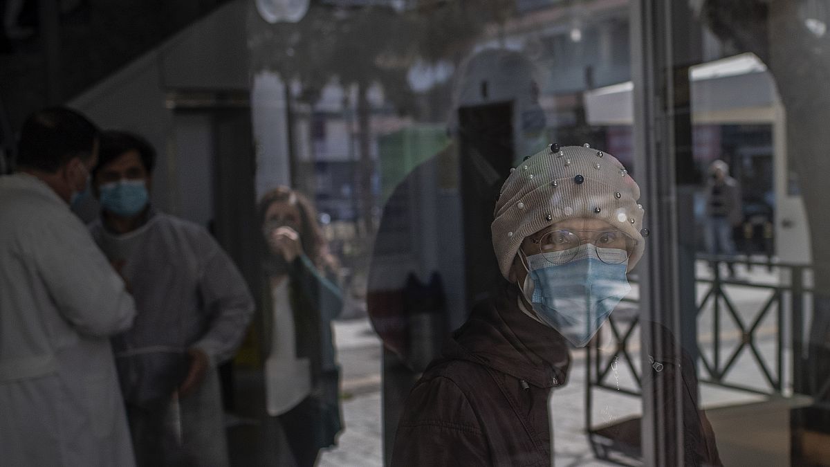Una señora sale de un centro de vacunación en Atenas llevando una mascarilla protectora