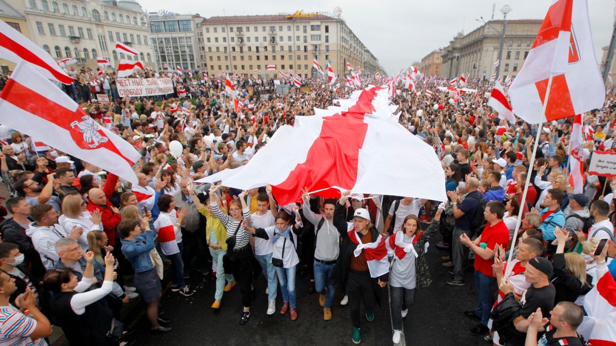 In this Sunday, Aug. 23, 2020 file photo, demonstrators carry a huge historical flag of Belarus as thousands gather for a protest at the Independence square in Minsk, Belarus.