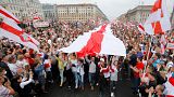 In this Sunday, Aug. 23, 2020 file photo, demonstrators carry a huge historical flag of Belarus as thousands gather for a protest at the Independence square in Minsk, Belarus.