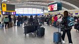 Passengers queue to check in, at Heathrow Airport in London. Passengers queue to check in, at Heathrow Airport in London.