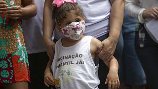 "Vacinação Infantil, Já!", lê-se numa blusa envergada por criança durante a manifestação pelas vacinas contra a covid-19