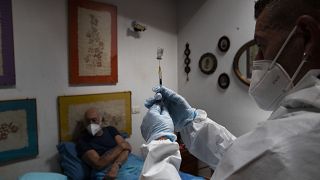Nurse Luigi Lauri prepares a dose of the Pfizer vaccine for 85-year old Giorgio Tagliacarne at his home in Rome, Tuesday, April 27, 2021
