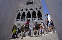Tourists walks on a bridge in front of Palazzo Ducale, in Venice, Italy, Thursday, June 17, 2021.