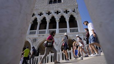 Tourists walks on a bridge in front of Palazzo Ducale, in Venice, Italy, Thursday, June 17, 2021.