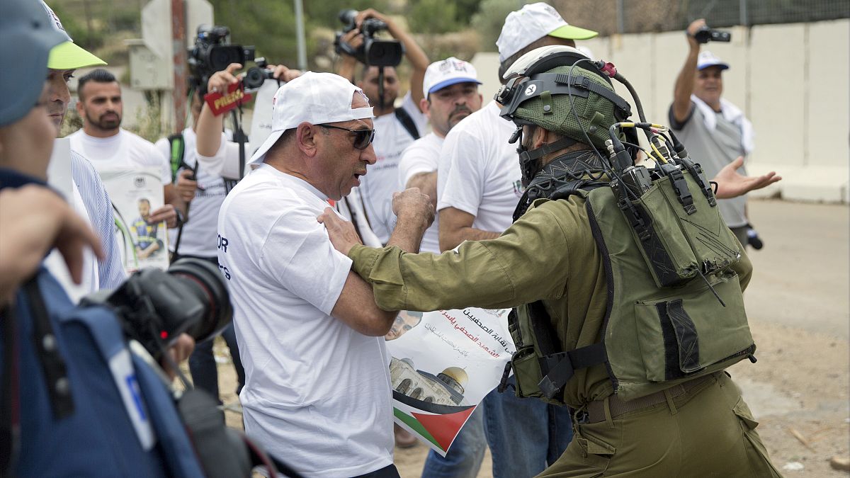 جندي إسرائيلي يدفع صحفي  فلسطيني، خلال مظاهرة نظمتها نقابة الصحفيين الفلسطينيين  بالقرب من مدينة رام الله الضفة الغربية.