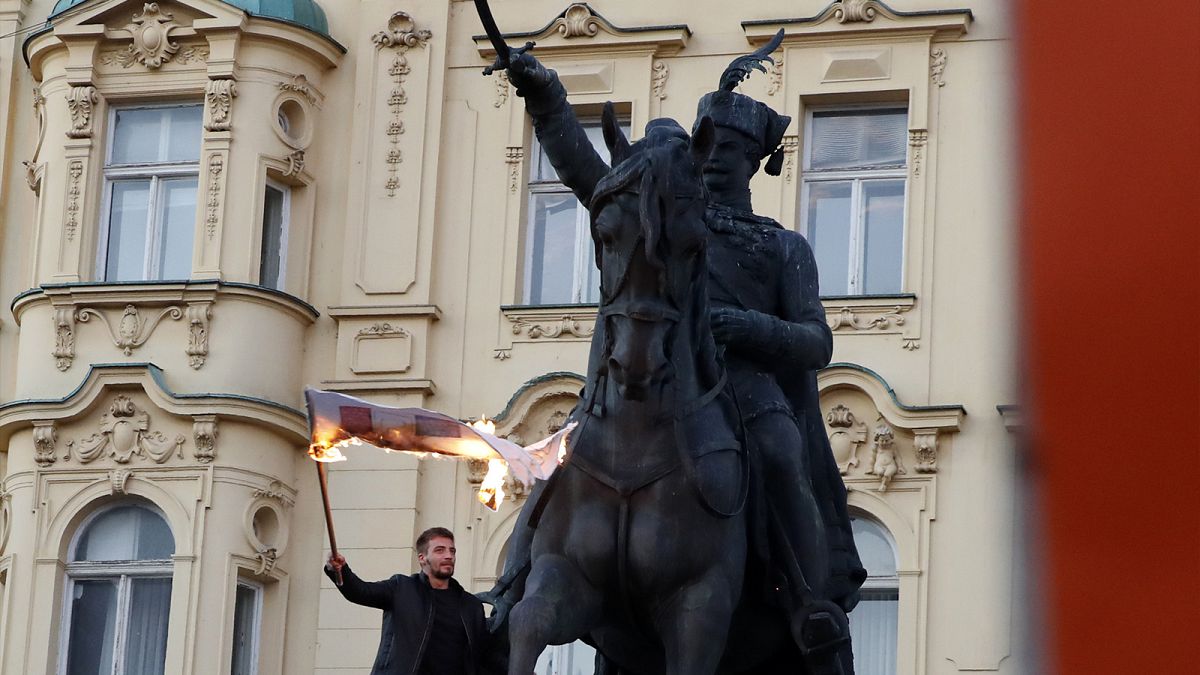 A man burns a flag during a protest against vaccination and coronavirus measures in Zagreb