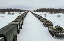 Vehículos militares rusos esperan para subir a aviones de transporte militar con destino a Kazajistán