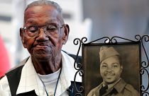 WWII veteran Lawrence Brooks holds a photo of him taken in 1943, as he celebrates his 110th birthday at the National World War II Museum in New Orleans, on Sept. 12, 2019.