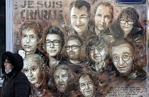 A woman walks past a mural payinng tribute to members of Charlie Hebdo newspaper who were killed by jihadist gunmen in January 2015, on January 6, 2022.
