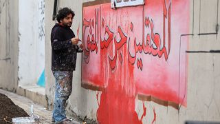 الفنان السوري عزيز أسمر يرسم جدارية كتب عليها "المعتقلون جرحنا المفتوح" حيث يشارك أهالي وأقارب المعتقلين والمفقودين في مسيرة للمطالبة بالإعلام عن ذويهم، في بلدة أعزاز.
