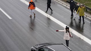 Environmental protesters stop cars on the highway during a protest in Belgrade, Serbia, Saturday, Jan. 8, 2022.