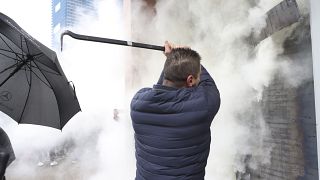 Employees of Democrats' Party use a fire extinguisher against protesters who try to invade at the headquarters in Tirana, Albania, Saturday, Jan. 8, 2022.