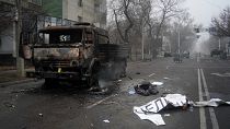 A body of victim covered by a banner, right, lays near to a military truck, which was burned after clashes, in Almaty, Kazakhstan, Jan. 6, 2022.