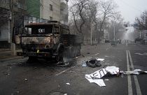 A body of victim covered by a banner, right, lays near to a military truck, which was burned after clashes, in Almaty, Kazakhstan, Jan. 6, 2022.