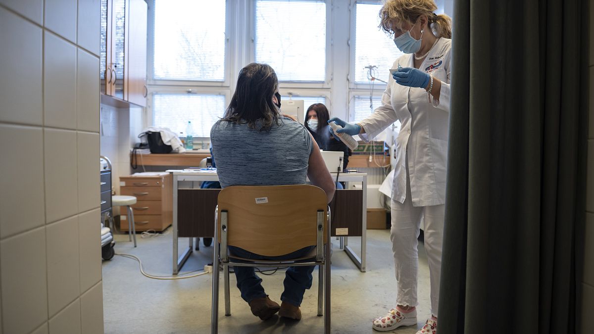 Fertőtlenítik egy férfi vállát, mielőtt megkapja a kínai Sinopharm koronavírus elleni vakcina második adagját a salgótarjáni Szent Lázár Megyei Kórház oltópontján