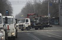 Aufräumen in Almaty: Ein ausgebranntes Fahrzeug wird abtransportiert
