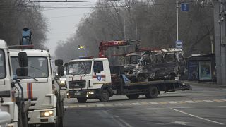 Aufräumen in Almaty: Ein ausgebranntes Fahrzeug wird abtransportiert