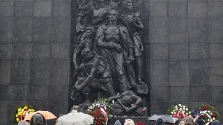 Tourists gather in front of the monument to the Heroes of the Warsaw Ghetto who fought in the 1943 uprising.