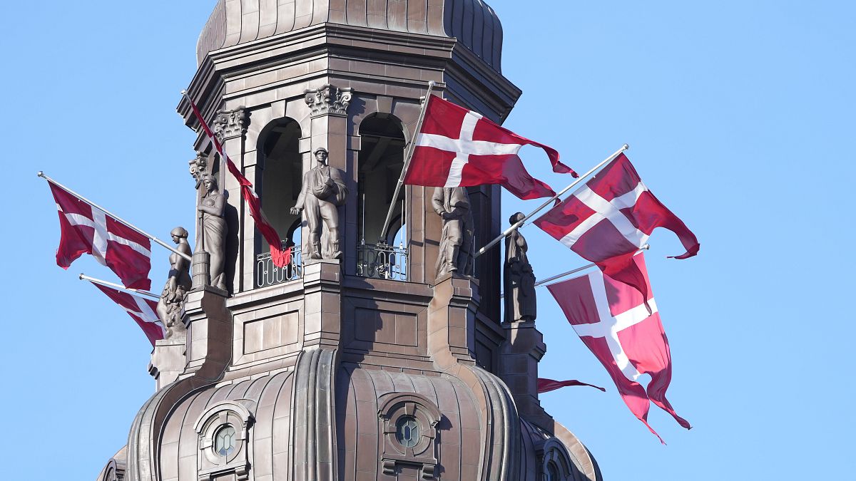 Danish flags are attached to the spire of the Danish Parliament building in Copenhagen.