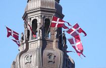 Danish flags are attached to the spire of the Danish Parliament building in Copenhagen.