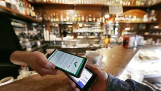 A customer gets his health pass checked at a snack bar in Rome, Monday, Jan. 10, 2022