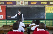 A teacher welcomes back students during a classroom lesson on day one of re-opening schools in Kampala, Uganda.