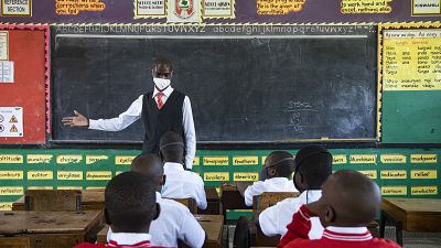 A teacher welcomes back students during a classroom lesson on day one of re-opening schools in Kampala, Uganda.