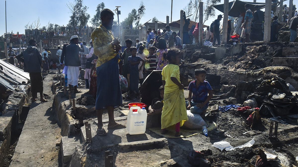 People gather on the ground of brunt-out houses after a fire gutted parts of a Rohingya refugee camp.