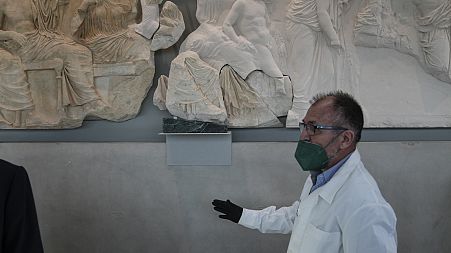 A conservator stands next to a Parthenon fragment, on loan from the Antonino Salinas Regional Archaeological Museum of Palermo, at the Acropolis Museum in Athens