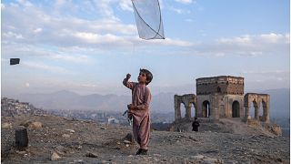 طفل يلهو بطائرة ورقية على تلة في كابول، أفغانستان.