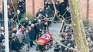 This picture made available by online news portal Open shows people gathered around a swastika-covered casket outside the St. Lucia church, in Rome, Jan. 1, 2022.