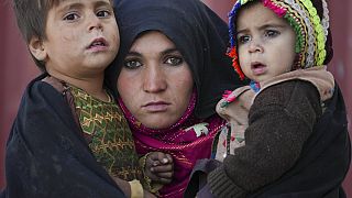 Afgán nő tartja kezében gyerekeit