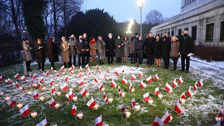 A koronavírus-járvány lengyel áldozatainak emlékére gyújtanak mécsest a lengyel szenátorok a szenátus varsói kertjében 2021. december 14-én.